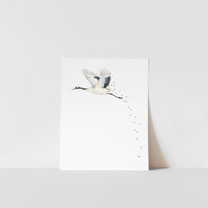 A art print of a Japanese crane with a blossom in its beak, printed on ultra premium matte paper with archival inks, signed by Heather S Vitticore.